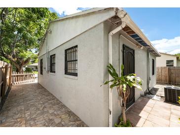 Side view of a single-story home featuring stucco walls, barred windows, and a stone-paved pathway leading to the entrance at 320 Eaton St, Maitland, FL 32751