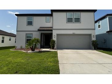 Two-story home with a well-manicured lawn, a gray two-car garage, and a cozy, covered front porch at 3823 Spruce Creek Dr, Lakeland, FL 33811