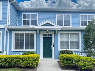 Charming two-story condo featuring a green front door, white trim, and manicured landscaping at 4011 Venetian Bay Village # 104, Kissimmee, FL 34741