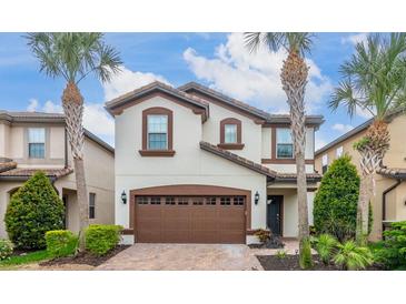 Charming two-story home featuring a brown garage door, tile roofing, and beautiful landscaping, including palm trees at 8912 Rhodes St, Kissimmee, FL 34747