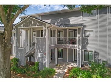 Inviting exterior view of condo featuring gray siding, stairs, and a small balcony at 2206 Stonington Ave # 2206, Orlando, FL 32817