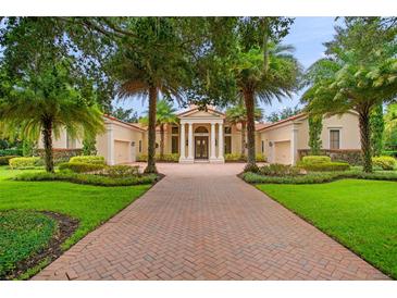 Elegant home featuring a brick driveway, manicured lawn, and tropical landscaping at 3426 Cocard Ct, Windermere, FL 34786