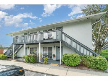 Two-story condo featuring a gray staircase and well-maintained landscaping, with a small seating area outside the entrance at 4890 Conway Rd # 66, Orlando, FL 32812