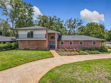 Charming brick home featuring a balcony, arched entryway, and well-manicured lawn at 1850 Lakeshore Cir, Longwood, FL 32750
