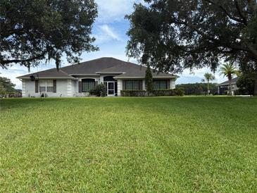 Charming single-story home featuring a well-manicured lawn and mature trees enhancing curb appeal at 23717 Milford Dr, Eustis, FL 32736