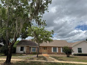 Charming single-story brick home featuring a well-maintained lawn, mature trees and inviting facade at 3917 Lake Mira Dr, Orlando, FL 32817