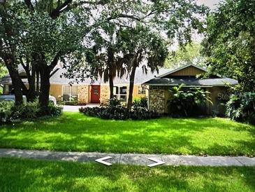 Charming single-story home featuring a red door and beautifully landscaped front yard with lush green grass at 4140 Winderlakes Dr, Orlando, FL 32835