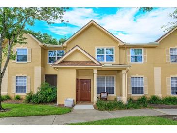 Charming two-story townhome with yellow siding, a well-manicured lawn, and a welcoming front porch area at 835 Grand Regency Pt # 104, Altamonte Springs, FL 32714