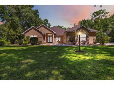 Charming one-story home featuring lush landscaping and a well-manicured lawn with a lamp post in the front yard at 21795 Sw 88Th Lane Rd, Dunnellon, FL 34431
