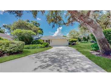 Charming home featuring a well-manicured lawn, lush landscaping, and a long driveway leading to a two-car garage at 42 W Grenewood Ln, Haines City, FL 33844