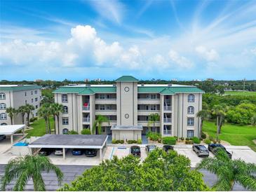 Multi-story condo building with parking, green roof and landscaping against a sunny sky at 426 Bouchelle Dr # 202, New Smyrna Beach, FL 32169