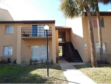 Two-story condo building featuring a balcony and staircase, surrounded by palm trees at 5220 Via Hacienda # 212, Orlando, FL 32839