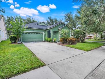 Charming green home featuring a lush landscaped yard, large driveway, and a well-manicured lawn at 5263 Beach River Road, Windermere, FL 34786