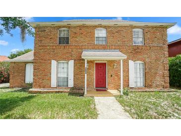 Charming brick two-story home featuring a bright red front door and white window shutters at 5891 Sir Henry Rd, Orlando, FL 32808