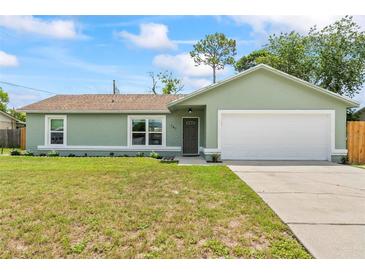 Charming single story home featuring a well-manicured lawn and a two-car garage at 705 Ibis Ave, Deltona, FL 32738