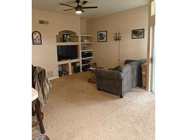 Comfortable living room featuring a ceiling fan and built-in shelves for decor at 7230 Westpointe Blvd # 1235, Orlando, FL 32835