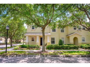 Charming yellow two-story townhome featuring lush landscaping and a welcoming front entrance at 13028 Auburn Cove Ln, Orlando, FL 32828