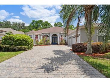 Charming home featuring a lovely paved driveway, lush landscaping, and a welcoming blue front door at 1542 Wescott Loop, Winter Springs, FL 32708
