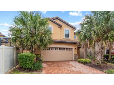 Stunning two-story home featuring a brick driveway, two-car garage, and beautiful palm trees at 2121 Morocco Way, Kissimmee, FL 34747