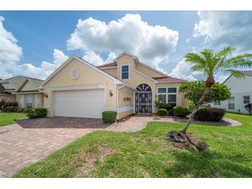 Charming single-story home featuring a manicured lawn, mature palm tree, and brick-paved walkway leading to the entryway at 3585 Ventura Club Cir, Orlando, FL 32822