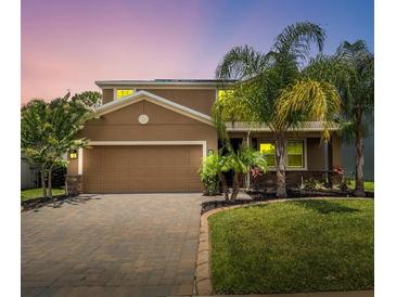 Charming two-story home features a well-manicured lawn, tropical landscaping, and a brick paver driveway at 461 Brunswick Dr, Davenport, FL 33837