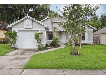 Inviting single-story home with well-maintained lawn, attached two-car garage, and charming landscaping at 1802 Waterbeach Ct, Apopka, FL 32703