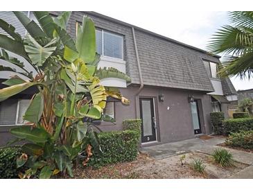Townhouse exterior showing dark grey paint, stone roof, green bushes, and unit numbers on each door at 1922 Conway Rd # 1922, Orlando, FL 32812