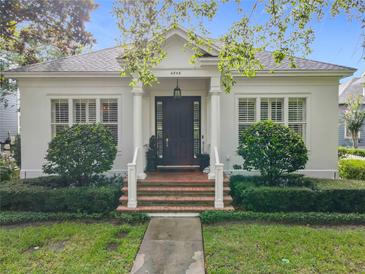 Charming home with a brick staircase leading to a dark wood front door framed by stately columns and lush landscaping at 4545 Fox St, Orlando, FL 32814