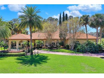 Stunning single-story home featuring a terracotta roof, lush landscaping, and a circular driveway at 3130 Butler Bay N Dr, Windermere, FL 34786
