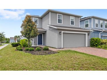 Charming two-story home featuring a well-maintained lawn, landscaping and brick-paved driveway at 4301 Creek Bank Dr, Kissimmee, FL 34744