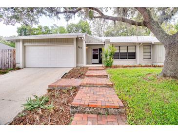 Charming single-story home with brick pathway and a well-manicured lawn under a mature tree at 452 Sundown Trl, Casselberry, FL 32707