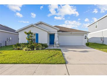Charming single-story home with a well-manicured lawn, blue shutters, and a two-car garage at 873 Daring Dr, Davenport, FL 33837