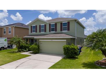 Charming two-story home featuring lush landscaping, an attached two car garage, and an inviting facade at 1951 Betsy Ross Ln, St Cloud, FL 34769
