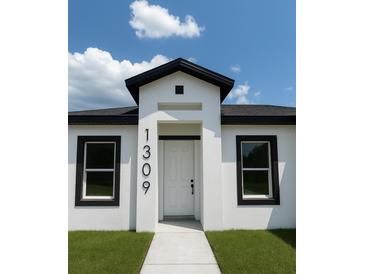 Modern home featuring a white exterior with black trim and a welcoming front entrance at 1309 Hillsborough Ln, Kissimmee, FL 34759