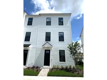 Charming three-story townhome features a brick facade, manicured lawn, and black framed windows at 15125 Grove Lake Dr, Winter Garden, FL 34787