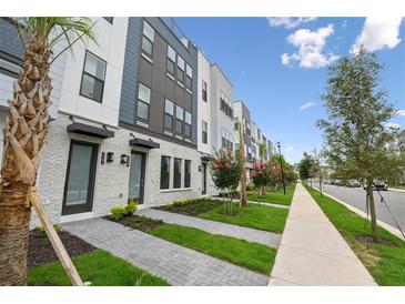 Modern townhouse exterior featuring brick accents, landscaping, and a sidewalk along the street at 2296 Brix Sts, Orlando, FL 32804