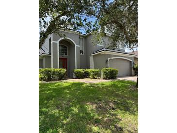 Two-story home featuring a well-maintained lawn, red front door, and a two-car garage at 5040 Rock Rose Loop, Sanford, FL 32771