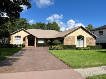 Charming single-story home featuring a brick exterior, tile roof, and a well-manicured lawn and landscape at 5416 Bay Side Dr, Orlando, FL 32819
