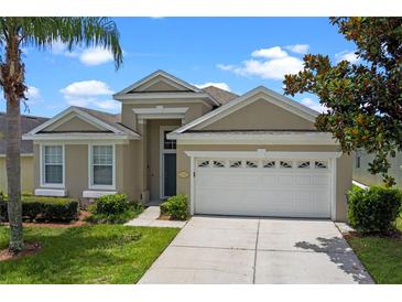 Charming home featuring a two-car garage, well-maintained lawn, and beautiful landscaping at 2222 Wyndham Palms Way, Kissimmee, FL 34747