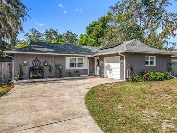 Charming single-story home with gray exterior, landscaped yard, and winding driveway under a sunny sky at 604 Thrush Ave, Longwood, FL 32750