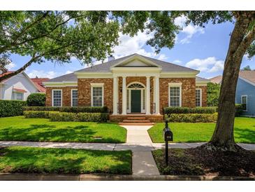 Charming brick home featuring stately columns, a well-manicured lawn, and beautiful landscaping at 922 Jasmine St, Celebration, FL 34747