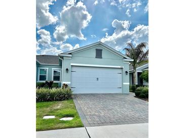 Charming single-Gathering home featuring lush landscaping, a paver driveway, and a two-car garage at 2042 Key Bay Trl, Kissimmee, FL 34747