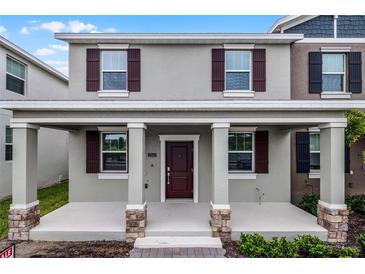 Charming two-story townhome featuring a covered porch and neutral-toned facade with contrasting shutters at 2563 Relaxing Ln, Kissimmee, FL 34744