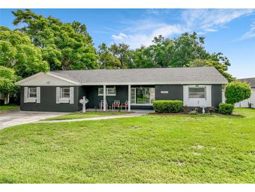 Charming single story home featuring a manicured lawn, mature trees, and a welcoming front porch at 3417 Pershing Ave, Orlando, FL 32812