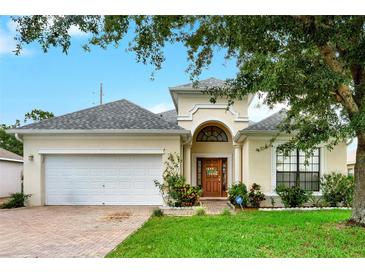 Charming single-Gathering home showcasing a well-manicured lawn, brick driveway, and attached two-car garage at 501 Lake Cummings Way, Lake Alfred, FL 33850