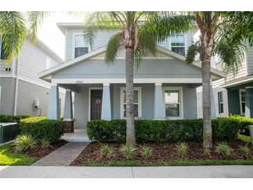 Charming home with well-manicured landscaping and inviting front porch framed by beautiful palm trees at 5963 Glory Bower Dr, Winter Garden, FL 34787