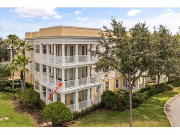 Three-story condo with multiple balconies, yellow and cream color scheme, and well-maintained landscaping at 7509 Mourning Dove Cir # 204, Reunion, FL 34747
