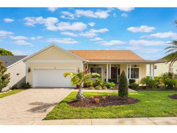 Charming single Gathering home with manicured lawn, brick driveway, and inviting covered porch at 930 Willow Oak Loop, Minneola, FL 34715