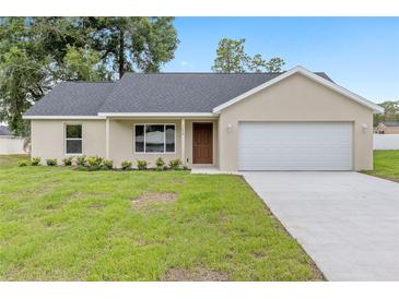 Charming single-story home featuring a two-car garage, well-maintained lawn, and neutral color palette at 1059 Ne 130Th Ter, Silver Springs, FL 34488