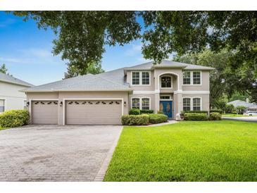 Charming two-story home boasts lush landscaping, a three-car garage, and a welcoming blue front door at 127 Heatherbrooke Cir, Oviedo, FL 32765